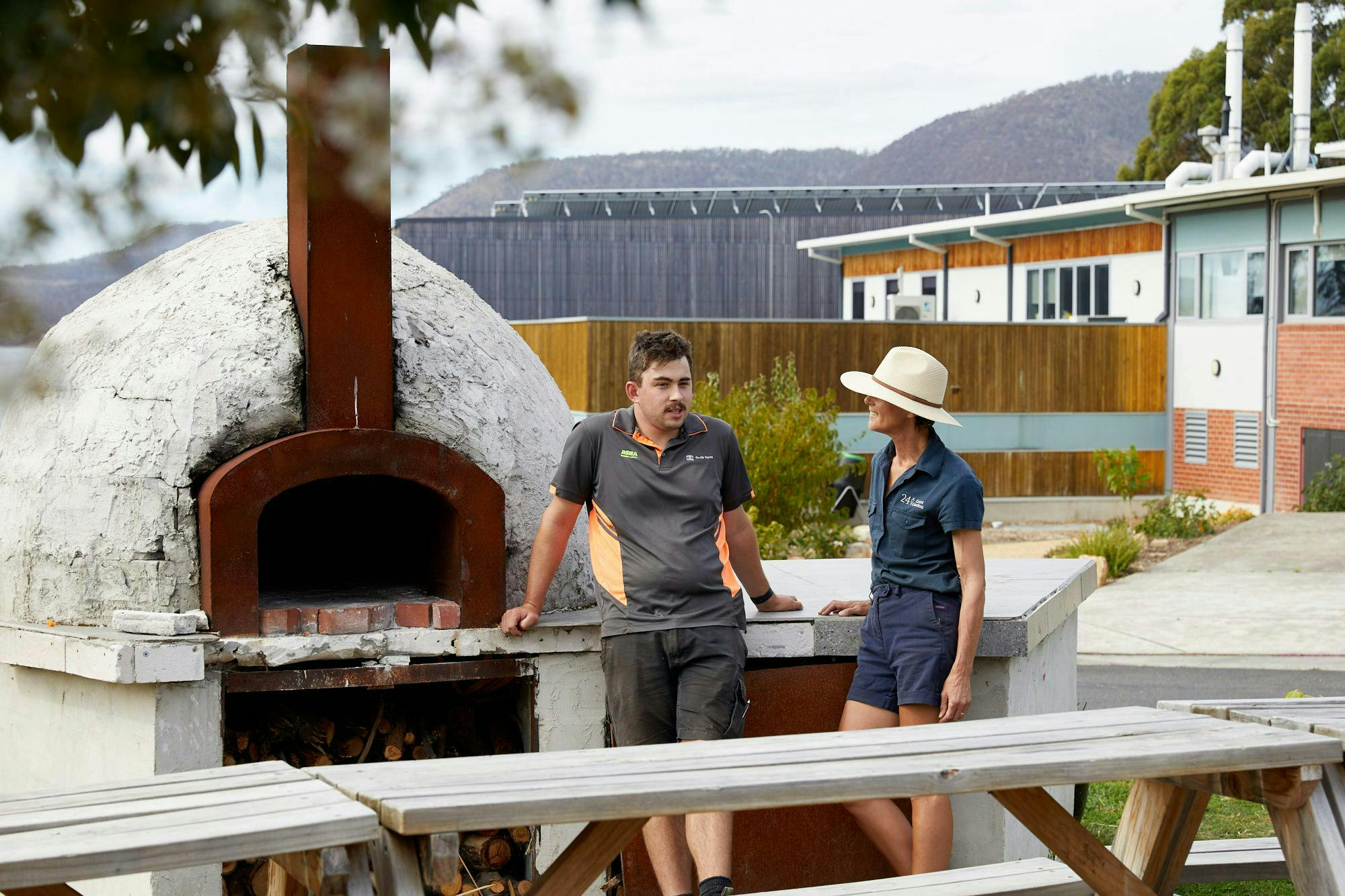 Ryan and Kris leaning next to the pizza oven at Montrose Bay Highschool