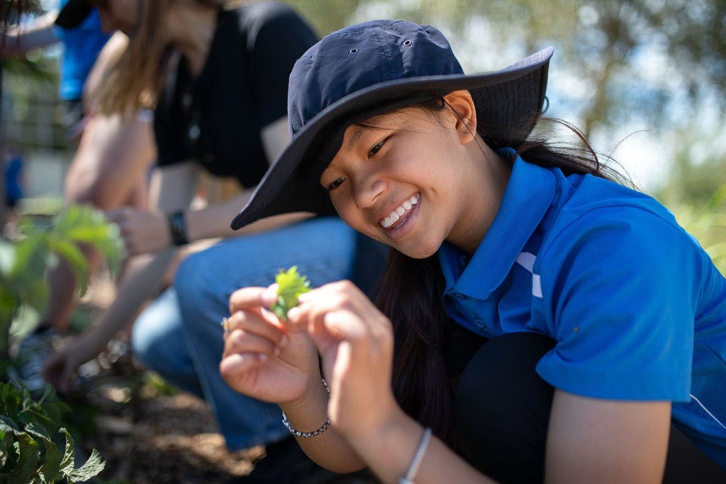 Student admiring plant in garden