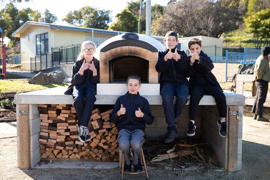 Students sitting on an outdoor pizza oven